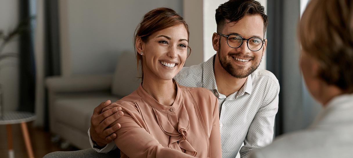 young happy couple shaking hands with insurance agent
